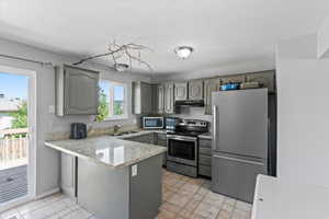 Kitchen featuring a peninsula, appliances with stainless steel finishes, and gray cabinets