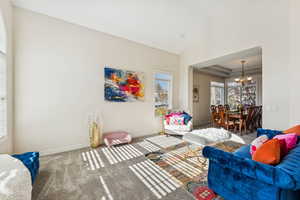 Living area with carpet floors, high vaulted ceiling, a chandelier, and a tray ceiling