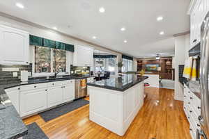 Kitchen with tasteful backsplash, recessed lighting, white cabinets, light wood-type flooring, and ornamental molding