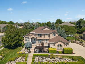 Traditional-style house with driveway, stairs, stone siding, and stucco siding