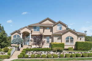 View of front facade with brick siding, stairway, and stucco siding
