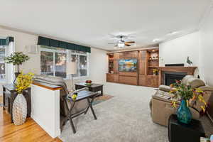 Living room featuring ornamental molding, a fireplace, ceiling fan, light wood-style flooring, and recessed lighting