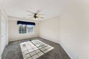 Carpeted empty room with baseboards and a ceiling fan