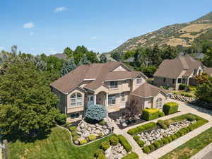 View of front of property with driveway, stucco siding, a mountain view, and stone siding