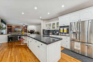 Kitchen with stainless steel appliances, recessed lighting, white cabinets, glass insert cabinets, and crown molding