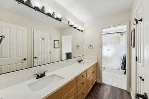 Full bath featuring double vanity, dark wood-style floors, and shower / tub combo with curtain