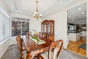 Dining area featuring a chandelier, light carpet, and a tray ceiling