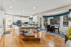Kitchen featuring tasteful backsplash, white cabinets, light wood finished floors, recessed lighting, and a center island