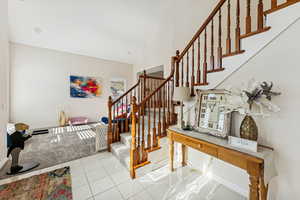 Stairway with tile patterned floors and high vaulted ceiling