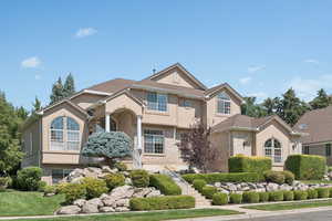 View of front of property featuring brick siding, stairway, and stucco siding