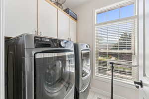 Laundry area featuring cabinet space, washer and clothes dryer, and light tile patterned floors