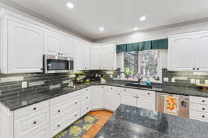 Kitchen featuring ornamental molding, appliances with stainless steel finishes, light wood-style floors, white cabinets, and recessed lighting