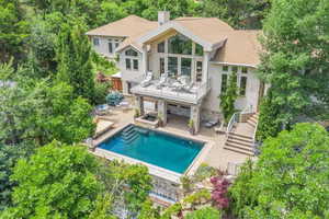 Rear view of house featuring a chimney, an outdoor pool, stucco siding, stairway, and a balcony