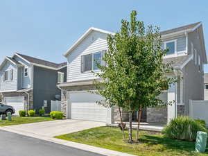 View of front of property featuring stone siding, an attached garage, and concrete driveway