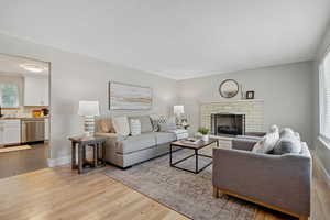 Living room with a stone fireplace, light wood-style flooring, and a textured ceiling