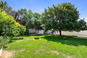 Fenced backyard with a playground, an outdoor fire pit, and a storage shed