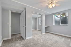 Unfurnished bedroom with carpet flooring, multiple windows, a closet, and a textured ceiling