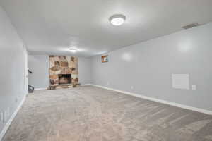 Finished below grade area featuring carpet flooring, a fireplace, and a textured ceiling