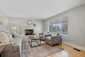 Living room with a fireplace, wood finished floors, and a textured ceiling