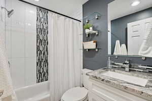 Full bathroom featuring vanity, shower / bathtub combination with curtain, and recessed lighting