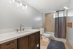 Full bathroom with vanity, shower / tub combo, tile patterned flooring, and a textured ceiling