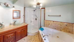 Full bath with vanity, a stall shower, and a whirlpool tub