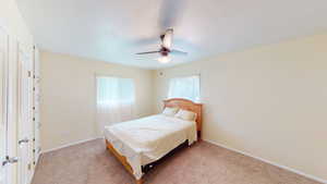 Carpeted bedroom with a ceiling fan and baseboards