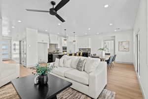 Living room with a ceiling fan, light wood finished floors, and recessed lighting