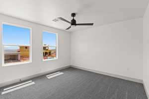 Carpeted empty room featuring baseboards and ceiling fan