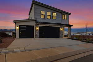 Modern home with concrete driveway, stone siding, a standing seam roof, and an attached garage