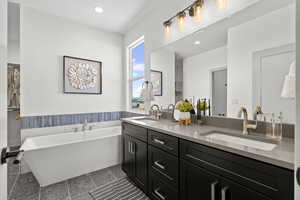 Full bath with double vanity, a freestanding bath, and recessed lighting