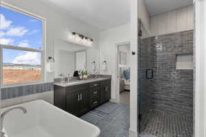 Bathroom featuring ensuite bathroom, double vanity, a soaking tub, a shower stall, and dark tile patterned flooring