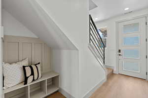 Foyer entrance with stairway and light wood-style flooring
