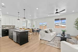 Dual tone kitchen with dual tone cabinetry, open floor plan, a kitchen island with sink, light wood-style flooring, and a kitchen breakfast bar