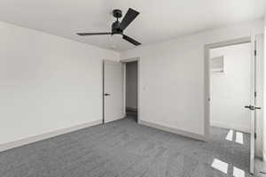 Unfurnished bedroom with carpet flooring, a walk in closet, and a ceiling fan