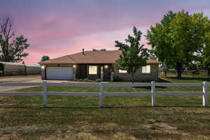 Ranch-style home with concrete driveway, brick siding, an attached garage, and a shingled roof