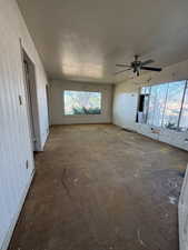 Unfurnished living room with a textured ceiling, arched walkways, and ceiling fan