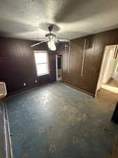 Bedroom featuring wooden walls, a textured ceiling, and ceiling fan
