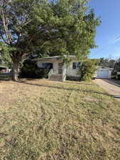 Single story home with a front yard and a detached garage