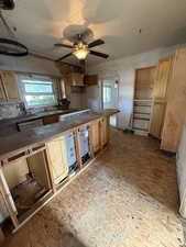 Kitchen featuring light brown cabinets, dark countertops, ceiling fan, and dishwasher