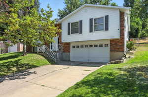 View of front facade featuring a garage, driveway, and brick siding