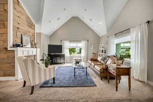 Living area with carpet floors, high vaulted ceiling, a brick fireplace, and recessed lighting
