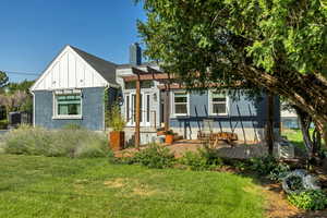 View of front facade with brick siding, a front yard, board and batten siding, and a wooden deck