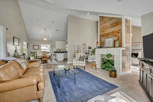Living room with recessed lighting, a fireplace, high vaulted ceiling, and light colored carpet
