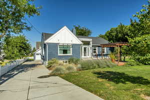 View of front of home featuring a pergola, board and batten siding, brick siding, a chimney, and roof with shingles