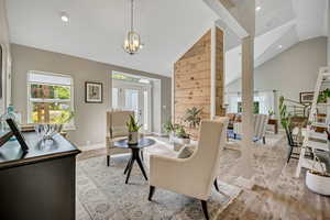 Sitting room with plenty of natural light, light wood-type flooring, lofted ceiling, recessed lighting, and a chandelier
