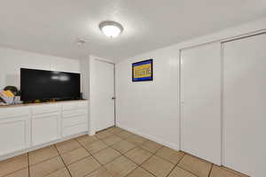 Unfurnished bedroom with a textured ceiling and light tile patterned floors