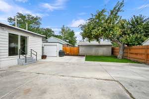 Fenced backyard featuring a patio area, an outdoor structure, grilling area, entry steps, and a garage