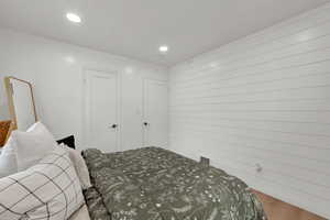 Bedroom with wood finished floors, recessed lighting, and wooden walls