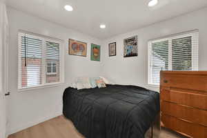 Bedroom with light wood-style flooring, multiple windows, and recessed lighting